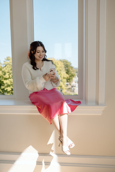 Shanté Gorman, founder of Sugarpunch Marketing®, a content marketing agency, sitting by a window and checking her phone.