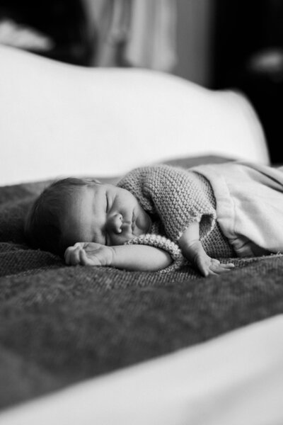 Baby wearing hand knit sweater sleeps on a cozy wool blanket