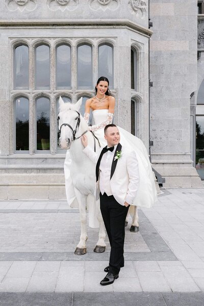bride in luxurious lace wedding gown posed by window
