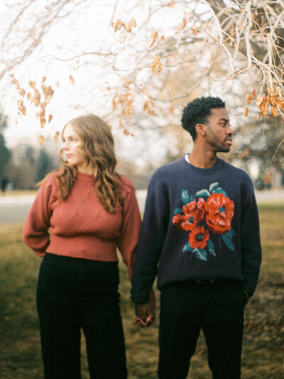 A couple holds hands in Cheesman Park during their engagement photos.