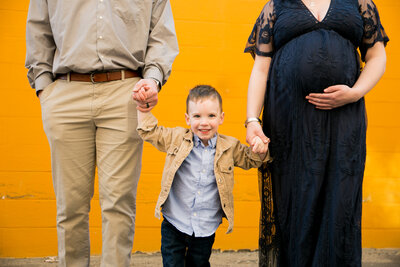 Photo of Parents holding son's hand and Mom holding pregnant belly