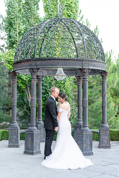 A bride and groom  holding hands under a pergola on the grounds of the Sleepy Ridge Golf Course  clubhouse