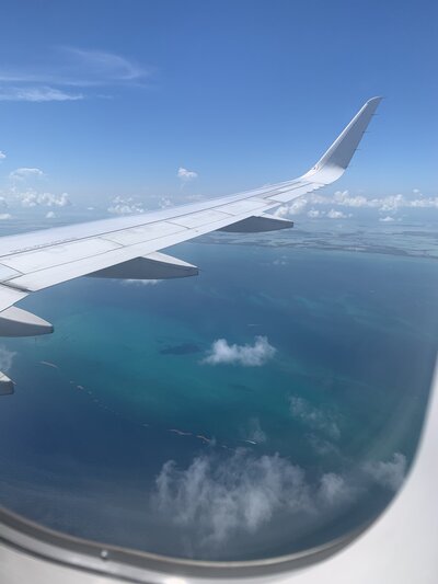 Airplane window view over turquoise ocean - wine country travel planning
