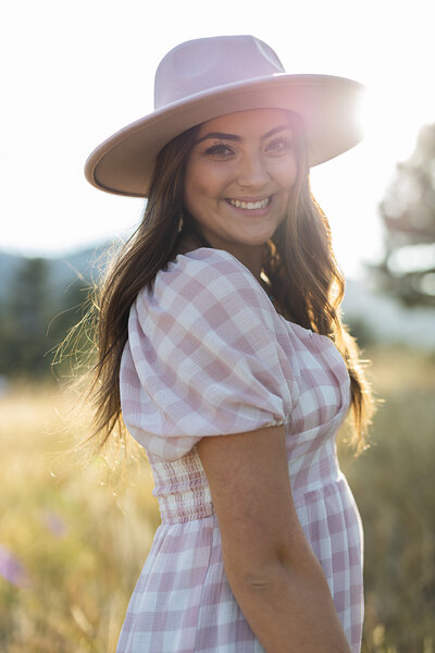girl posing for a photo with a pink dress and a hat at the sunset light in Boulder CO