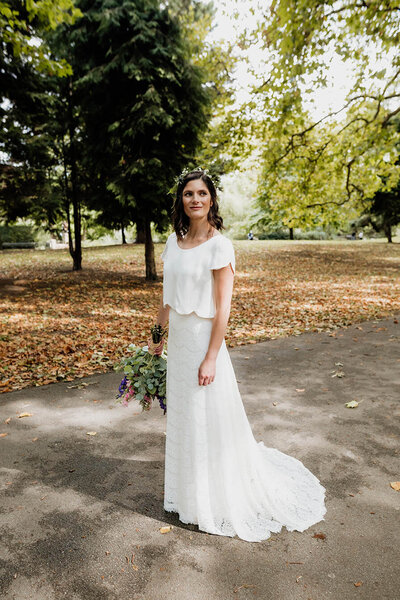 bride in southwark park after dilston grove wedding, long white skirt and lace top, flowers in hair