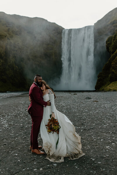 Bride and groom standing in front of Skogafoss during their iceland elopement
