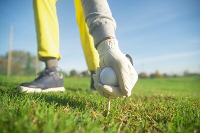 Renee O’Higgins, PGA and LPGA golf instructor Teach Me To Golf golfball with logo teeing up.