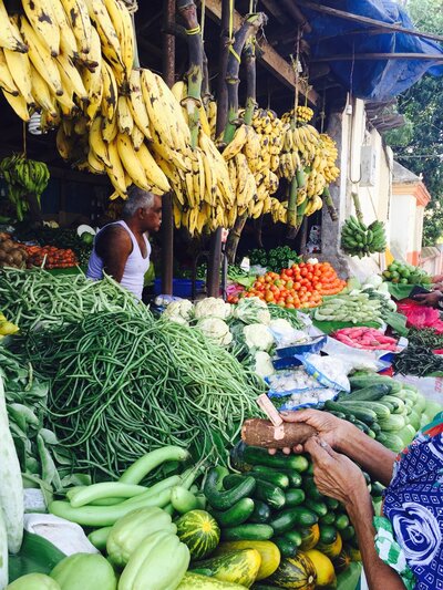 A wedding couple standing on steps leaning against a railing looking at each other. The bride is wearing a above knee white dress with a brown fur coat and white sunglasses, and the groom is wearing a black tuxedo with brown shoes.
