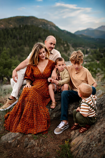 Family of five sitting on a boulder in estes park colorado wearing coordinated clothing. 