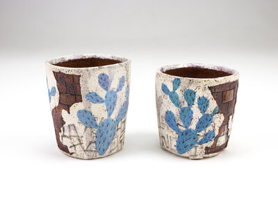 A ceramic cup that resembles plaster falling apart from red bricks with painted cacti and graffiti
