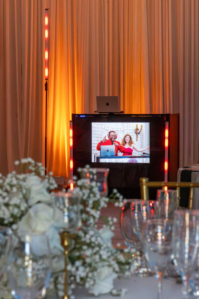 DJ booth with screen and floral table setup
