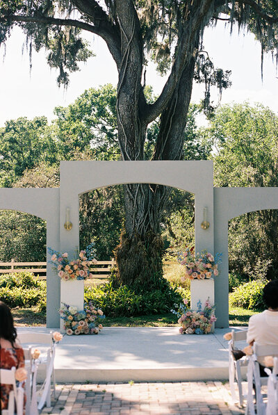 Bride and groom holding hands and smiling under a canopy of oak trees at Uliana Estate in Lakeland, Florida during summer