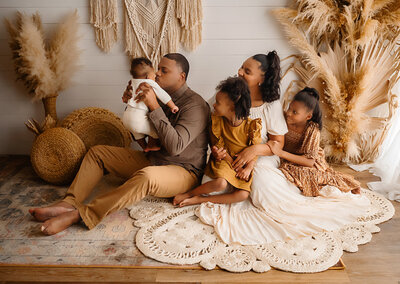 Family studio sessions are one of the sweetest session-capturing the connection with the family at Paula Goforth's Studio in Fort Worth Texas. Family wearing neutral colors that compliment the background that is boho styled.