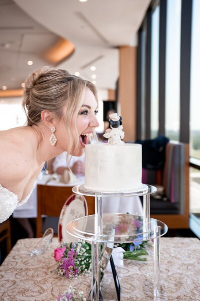 bride pretends to take a bite out of Disney themed wedding cake