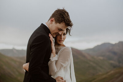 Couple snuggles together in the mountains during their elopement