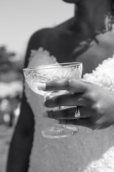Black and white photo of a  bride's hand holding a champagne glass