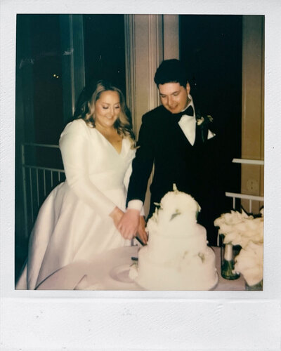 A polaroid photo taken as the bride and groom cut the cake together