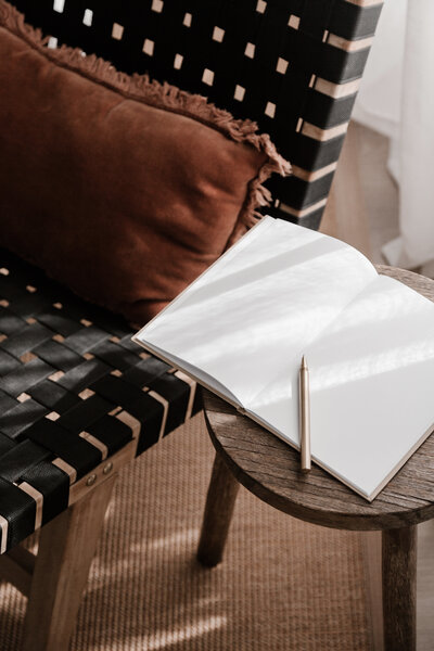 Moderner Flechtsessel neben einem Holztisch mit aufgeschlagenem Notizbuch im Fotografie & Design Studio in Zirndorf.