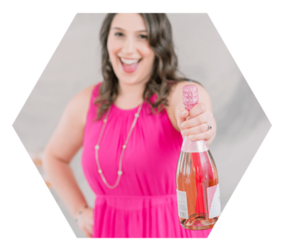Isabel Kateman wearing a pink dress and holding a bottle of champagne