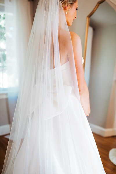 Close-up of a bride in a wedding gown with a bow detail and veil while getting ready for her Maine wedding.