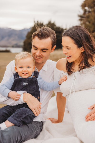 a family sitting in the grass pointing at the sky during their Queenstown family photoshoot