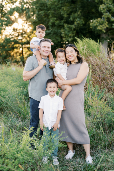 Mom and dad with 3 boys laugh during playful family photo session in Raleigh