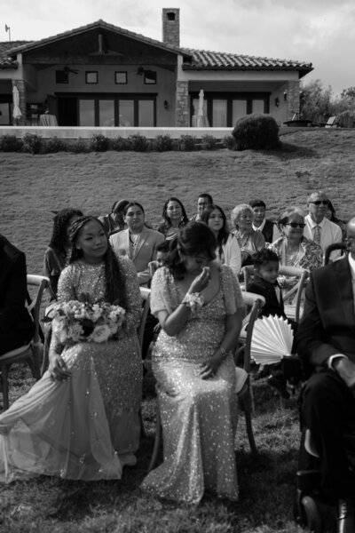 Mother of bride crying during the wedding ceremony for her daughter, in black and white.