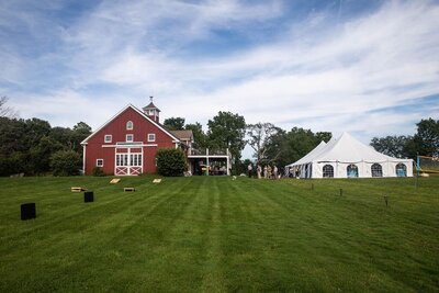 Venue photo from party located at a red barn with green grass and a bright blue sky.