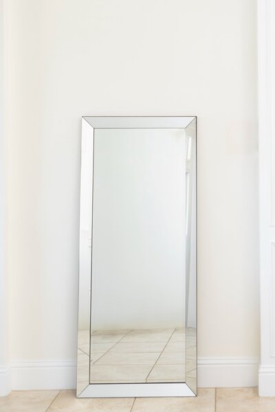 Silver framed rectangular mirror leaning against wall