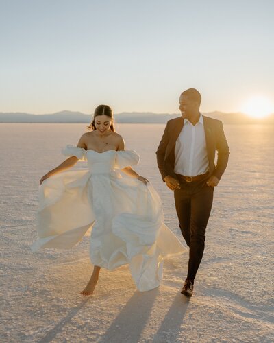 bride and groom running through sand dunes