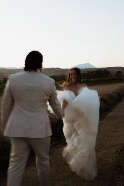wedding couple running in the fields at Kooroomba Vineyard and Lavender Farm