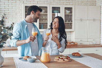 healthy couple enjoying breakfast with glasses of orange juice