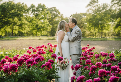 bride and groom kiss during wedding ceremony in boston flower field