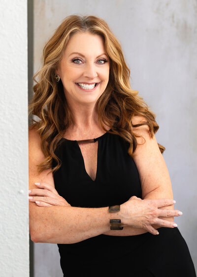 A head shot of Jen smiling in a black coat and green frilled top.