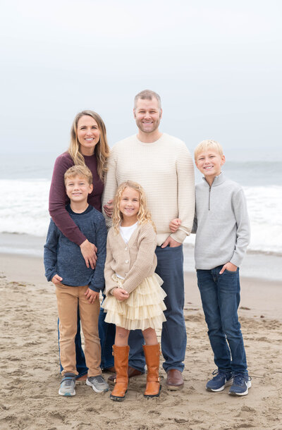 Family smiling during overcast beauty in Baker Beach, California