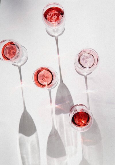 an above show of glasses of rose in wine glasses with shadows reaching long past them for product photography socialfizz