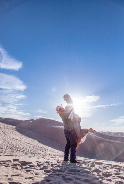 engaged couple embraces in yuma sand dunes