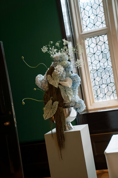 Statement floral installation featuring blue and white hydrangeas with tropical foliage.