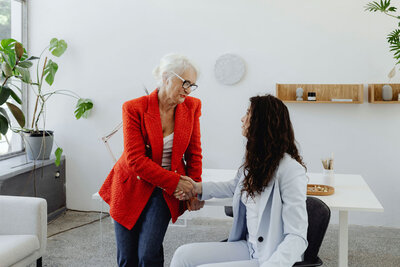 two woman in business suits shaking hands