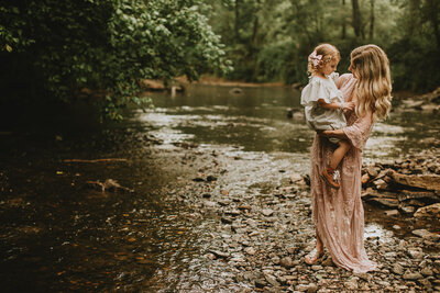 Family Photographer, mother holding daughter next to river