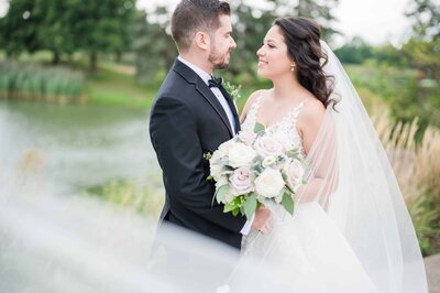 Romantic wedding portrait with bride and groom staring at each other in a beautiful garden.