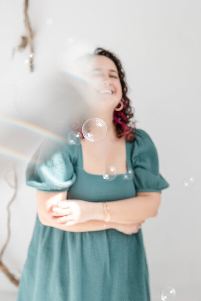 Laura is blurry in the background, surrounded by rainbow reflections and bubbles
