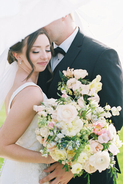 bride and groom snuggling in trees