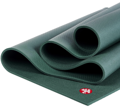 A dark green Manduka yoga mat rolled up with the signature red logo visible on the corner. The mat has a textured, non-slip surface and is known for its durability and support.