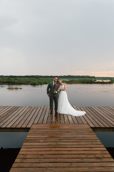 Standing lakeside with the sun setting behind the couple