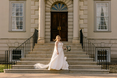 Wedding Photographer, Bride stands on steps to large estate