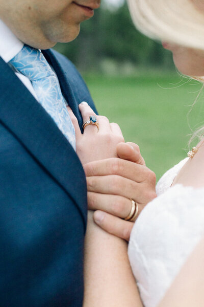 Close-up of bride's sapphire engagement ring and groom's wedding band during a luxury Montana wedding.