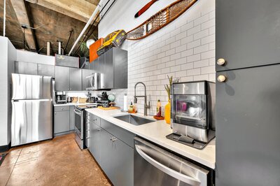 Kitchen with stainless steel appliances in this two-bedroom, two-bathroom vacation rental condo in the historic Behrens building in downtown Waco, TX just blocks from the Silos, Baylor University, and Spice Street.