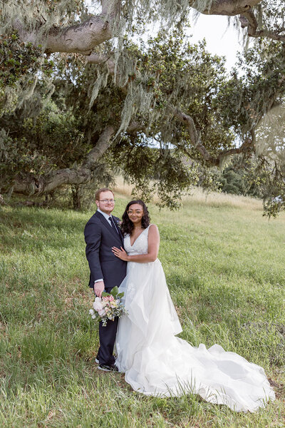 A couple posed in front of a tree on the groom's family property for their wedding