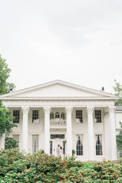 Bride and groom stand in front of Whitehall wedding venue in Louisville